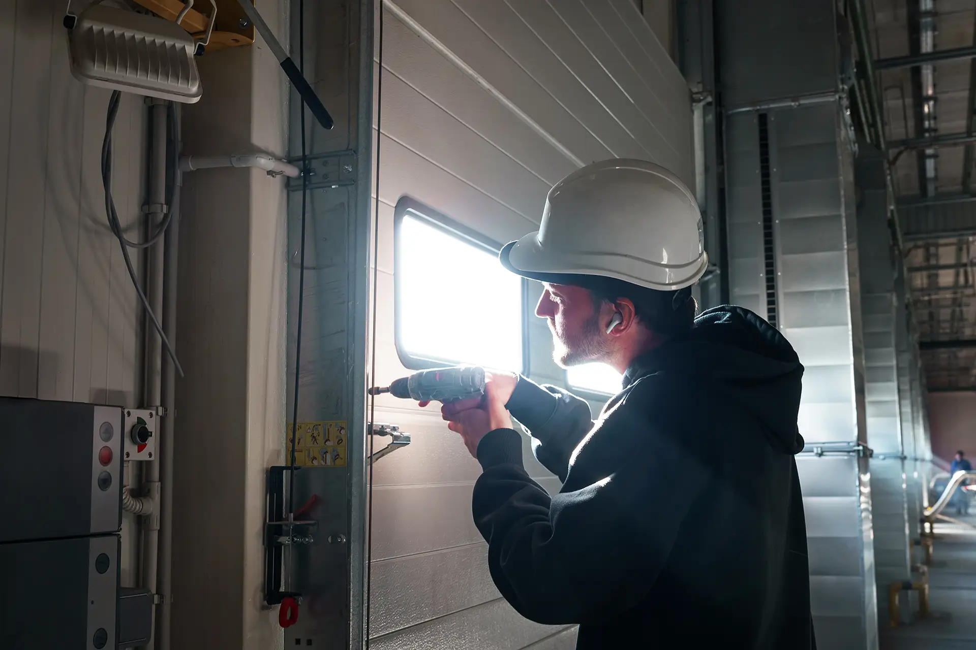 man with drill in hand installing door thing